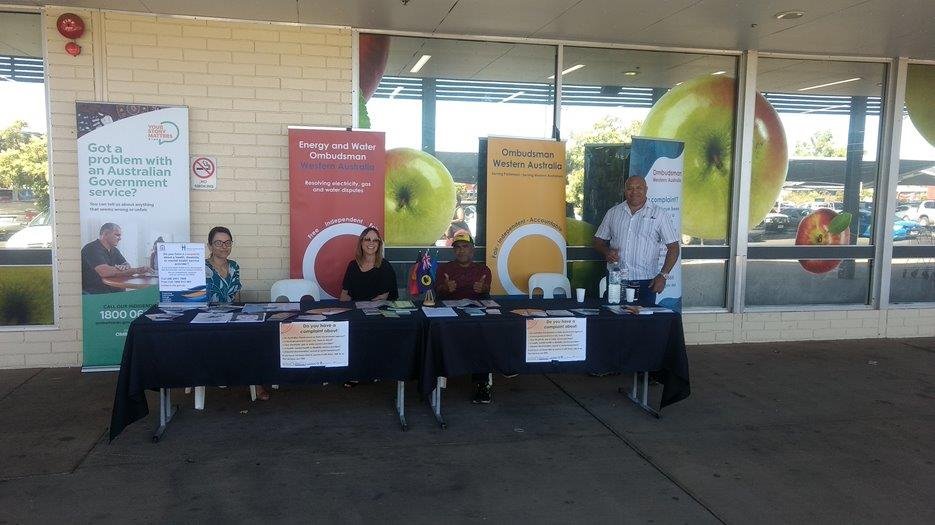Four staff sit behind an information stall table with banners in Kalgoorlie
