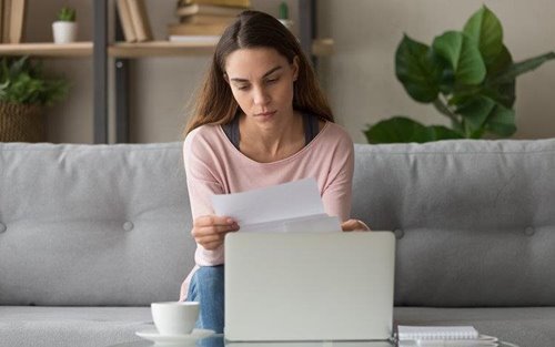 Women with laptop open reading a bill